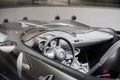 Side close up view of modern roofless grey sport coupe car interior: dashboard, helm, with hood, mirror, fuel tank cover