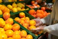 Side close up view of unrecognizable young woman trying to choose and pick oranges in the supermarket while grocery shopping Royalty Free Stock Photo