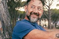 Side closeup portrait of adult man with beard smiling and enjoying relax time at the park. Happy and serene people with cheerful