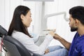 Side closeup view of attractive male dentist checking and selecting color of young asian woman teeth Royalty Free Stock Photo