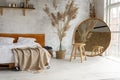 Side closeup view on spacious white eco style loft bedroom with bed,  mirror and pampas grass decoration Royalty Free Stock Photo