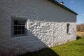 Side of a colonial American white stone cottage with shadows