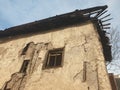 Side facade of an old rotten abandoned building with broken windows and peeling stucco