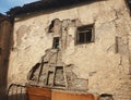 Side facade of an old rotten abandoned building with broken windows and peeling stucco