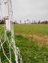 Side of a football goal post with net in focus. Training pitch out of focus. Soccer theme background