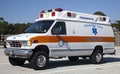 Side and front view of parked orange and white ambulance
