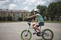 Side full-length of an active sporty child boy in protective sports helmet, riding a bicycle in the city asphalt road