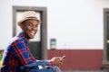 Side of handsome young african american man smiling with cellphone outdoors Royalty Free Stock Photo