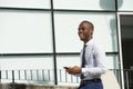 Side of happy african american businessman walking with cellphone in city Royalty Free Stock Photo