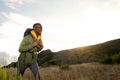 Side of happy young african american man hiking with backpack in the mountains Royalty Free Stock Photo