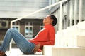 Side of happy young african American woman sitting on steps outside Royalty Free Stock Photo