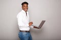 Side of happy young black man holding cellphone by gray wall Royalty Free Stock Photo