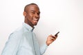 Side of happy young black man holding cellphone by white background Royalty Free Stock Photo