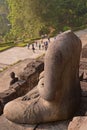 Side of Headless Statue at Borobudur Temple with tourists in the background