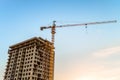 Side high-rise tower crane with a multi-storey building under construction against the blue sky Royalty Free Stock Photo