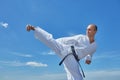 Side kick is trained by an athlete against a blue sky
