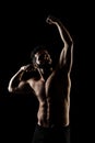 Side lit muscular Caucasian man silhouette. Athlete posing against black background