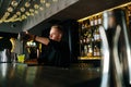 Side low-angle view of barman pouring fresh alcoholic drink into glasses with ice cubes behind bar counter in modern Royalty Free Stock Photo