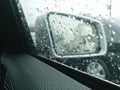Side mirror with the rain drops rolling on window on the road with traffic jam in the rainy day. Royalty Free Stock Photo