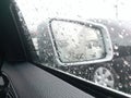 Side mirror with the rain drops rolling on window on the road with traffic jam in the rainy day. Royalty Free Stock Photo