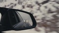 Side Mirror Showing Another Car Following. Winter Atmosphere. Concept of Chase