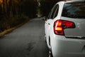 Side mirror turn signal blinker. Turn indicator on the mirror left and white car on the road in autumn dark forest. Royalty Free Stock Photo