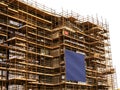 Side of a new building in scaffolding and safety nets and blue color banner. Construction site safety measures. Developing Royalty Free Stock Photo