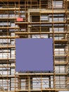 Side of a new building in scaffolding and safety nets and blue color banner. Construction site safety measures. Developing Royalty Free Stock Photo