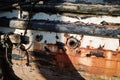 side of a old wooden hulled boat flaking paint rust marks and rotten timbers