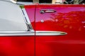 Side of an open bright red vintage retro convertible car with chrome details and moldings exhibited at a provincial town street