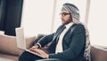 Side photo of Arab looking in Laptop on couch