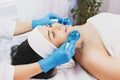 calm patient woman undergoing the cosmetic facial massage procedures for rejuvenation skin face and doctor using Royalty Free Stock Photo