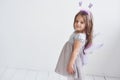Side photo. Lovely little girl in the fairy costume standing in room with white background