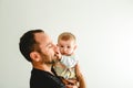 Side portrait of adorable baby in his father`s arms touching his face with his little hands, white background Royalty Free Stock Photo