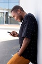 Side portrait african young man leaning on wall using mobile phone Royalty Free Stock Photo