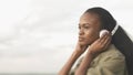 Side portrait of the attractive young african girl with natural make-up is listening to music in the headphones at the