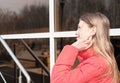 side portrait of a beautiful teenager girl wearing red jacket and looking aside. girl touching her hair on a windy day Royalty Free Stock Photo