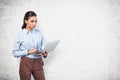 Side portrait of beautiful young businesswoman with long hair holding laptop standing over gray background. Concept of technology Royalty Free Stock Photo