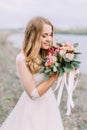 Side portrait of the bride smelling the wedding bouquet. The beach location. Royalty Free Stock Photo