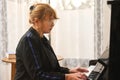 Portrait of mature woman, pianist performing classic melody on grand piano at home, sitting alone at vintage black piano Royalty Free Stock Photo