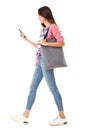 Side portrait of fashionable young asian woman walking with purse and mobile phone against isolated white background Royalty Free Stock Photo