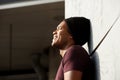 Side portrait of handsome young african american man leaning against wall and smiling Royalty Free Stock Photo