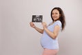 Happy attractive woman, expectant pregnant gravid mother smiling and showing at camera her future baby ultrasound scan Royalty Free Stock Photo