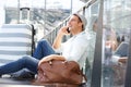 Happy travel man sitting on floor with suitcase bags and talking on mobile phone at station Royalty Free Stock Photo