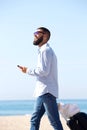 Side of happy traveler walking on beach with luggage and mobile phone