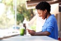 Happy young african woman sitting at cafe using mobile phone Royalty Free Stock Photo