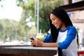 Happy young african woman sitting at outdoor cafe using cellphone Royalty Free Stock Photo