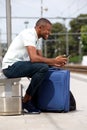 Young black man waiting at railway station with phone Royalty Free Stock Photo