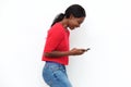 Side of happy young black woman looking at cellphone against white wall Royalty Free Stock Photo