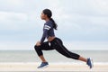 Side portrait of healthy young african american woman stretching muscles at the beach Royalty Free Stock Photo